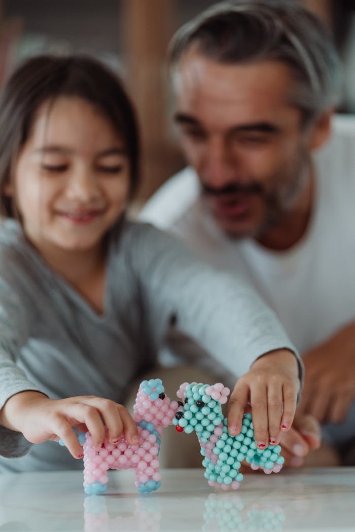 Father and daughter smiling while playing with colorful toy dogs indoors.